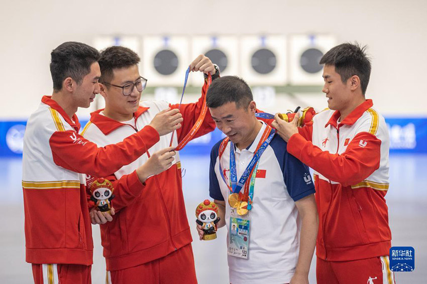 청두에서 열린 제31회 하계세계대학경기대회 사격 종목 남자 25m 속사 권총 단체전에서 샤치(夏琦), 류솨이(劉帥), 돤즈청(段志成)으로 구성된 중국팀이 금메달을 획득했다. 사진은 중국팀 선수들이 코치에게 메달을 걸어주고 있는 모습. [7월 30일 촬영/사진 출처: 신화사]